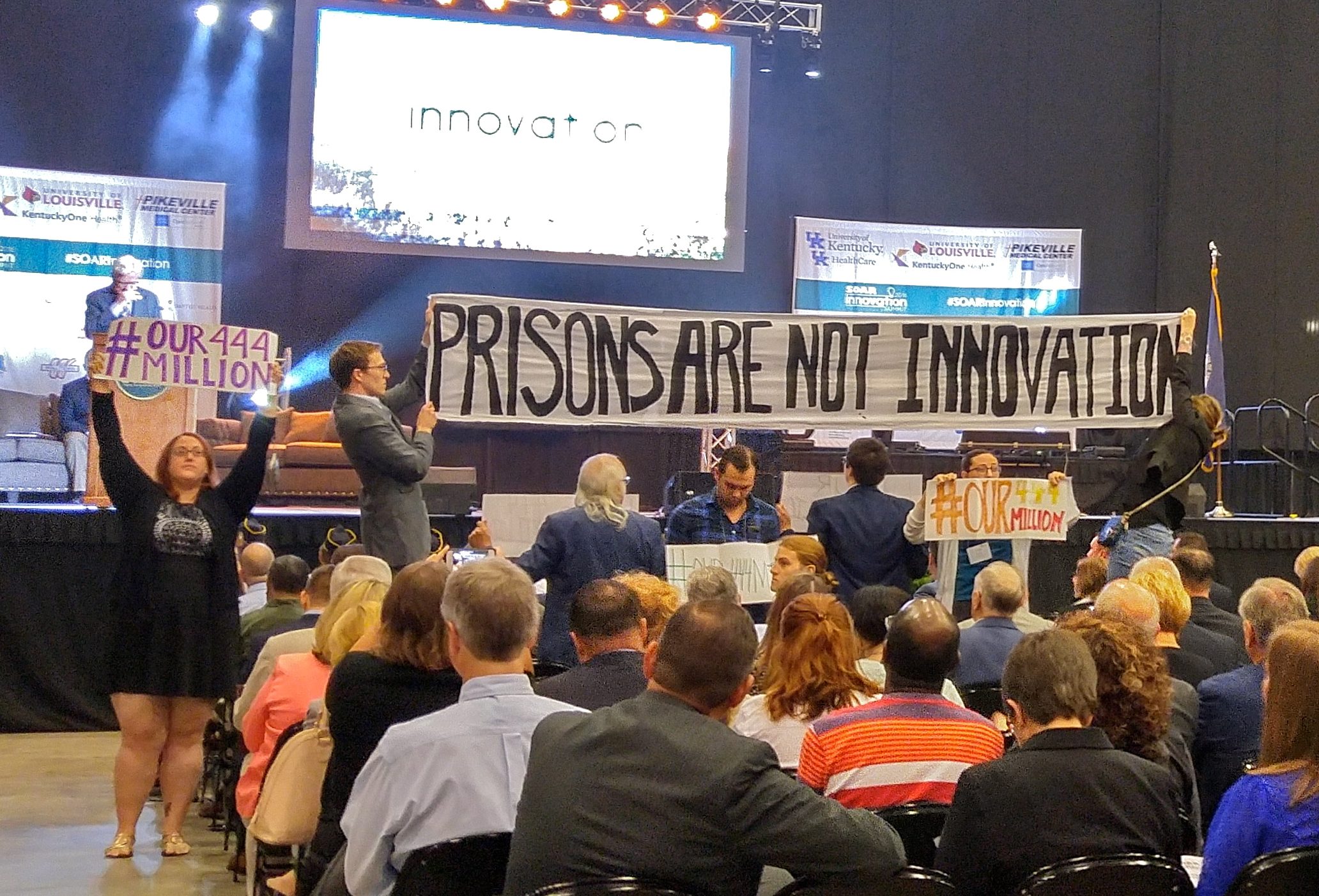 Tarence Ray holds up the left side of a banner protesting plans to build a new prison.