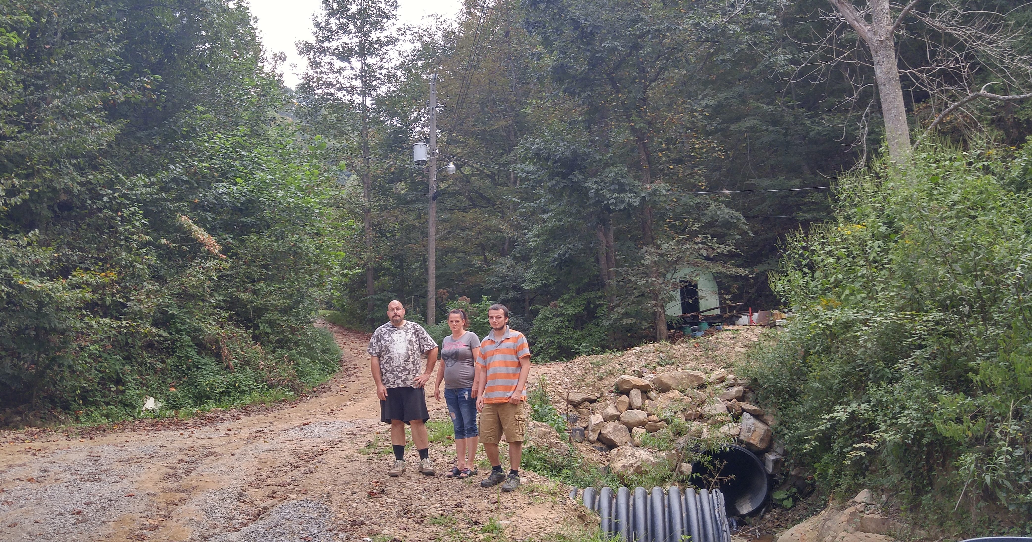 Chad Keene, Mollie Smith, and Toby Daniels stand on the driveway that was washed out and then rebuilt by Justice’s company. 