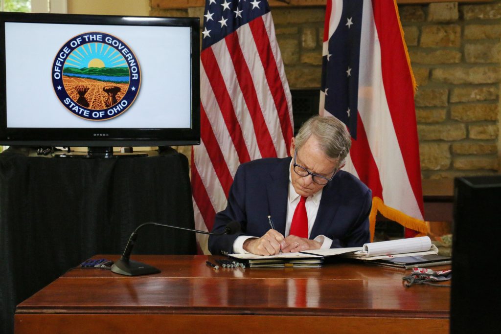 Ohio Gov. Mike DeWine signing a document. 