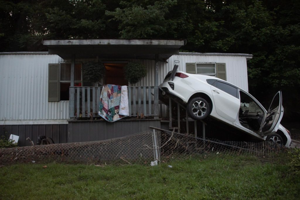 A car swept onto a porch after flooding.